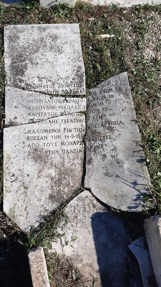A grave with a broken plaque and names. A piece of the plaque is missing.