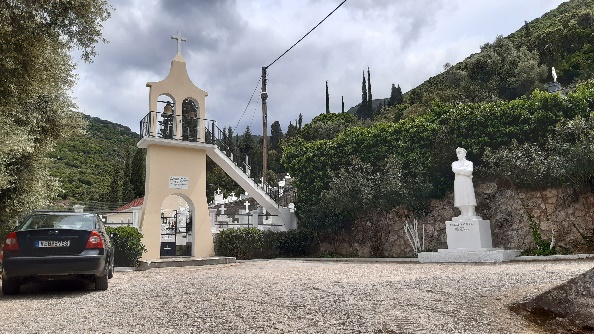 A statue on white marble on a plateau outside a cemetery. A standing officer with his arms crossed on his chest.